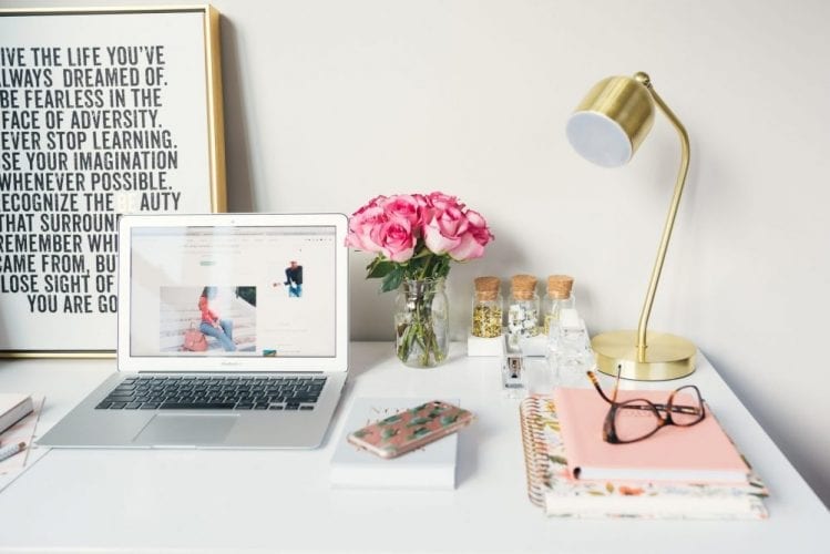 10 ting å vurdere før du velger hva bloggen skal handle om en skrivepult med lampe, Mac, notatbøker, mobil, briller, blomster og bilde med ord